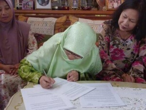 Cik Wan Nur Shazwani signing the scholarship agreement while YTAH Director, Puan Ellina looks on